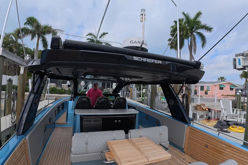 Slide: The Image of 2025 Schaefer V44 yacht interior with modern seating and navigation equipment, docked near palm trees. - 27