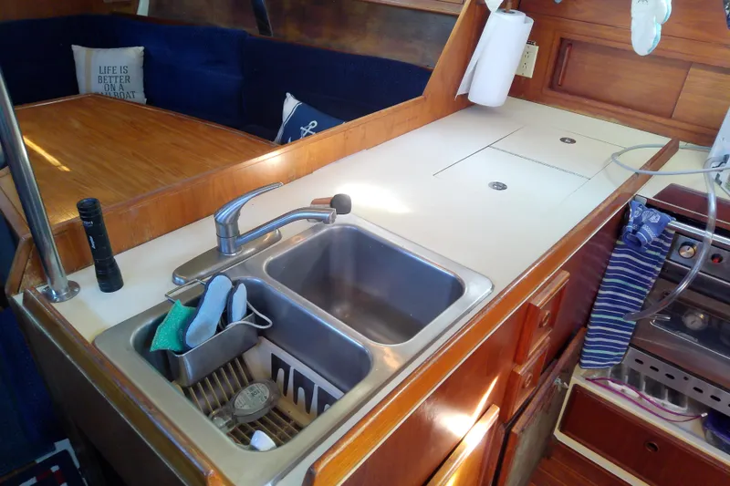 Slide: The Image of 1988 Pearson 36-2 yacht interior with kitchen sink, wooden cabinetry, and cozy seating area. - 32