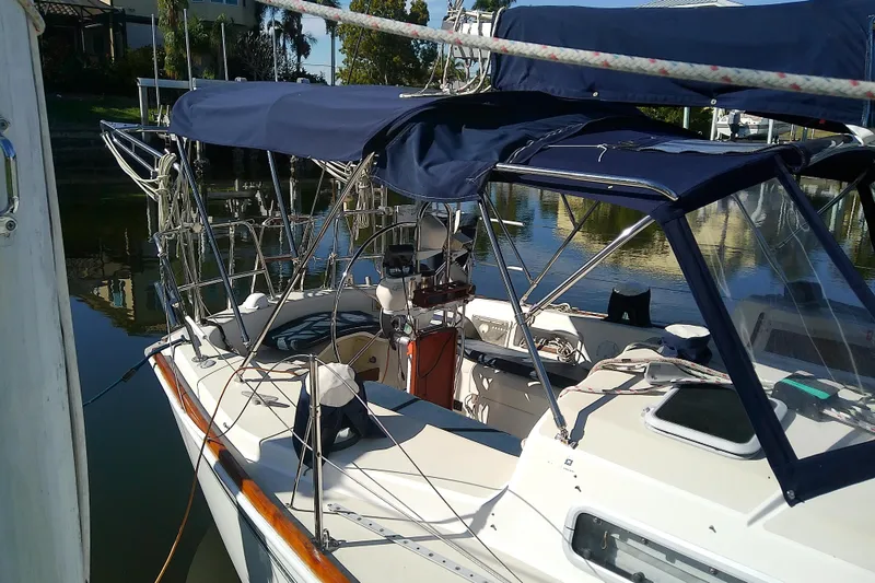 Slide: The Image of 1988 Pearson 36-2 sailboat with blue canopy docked in a serene marina. - 4