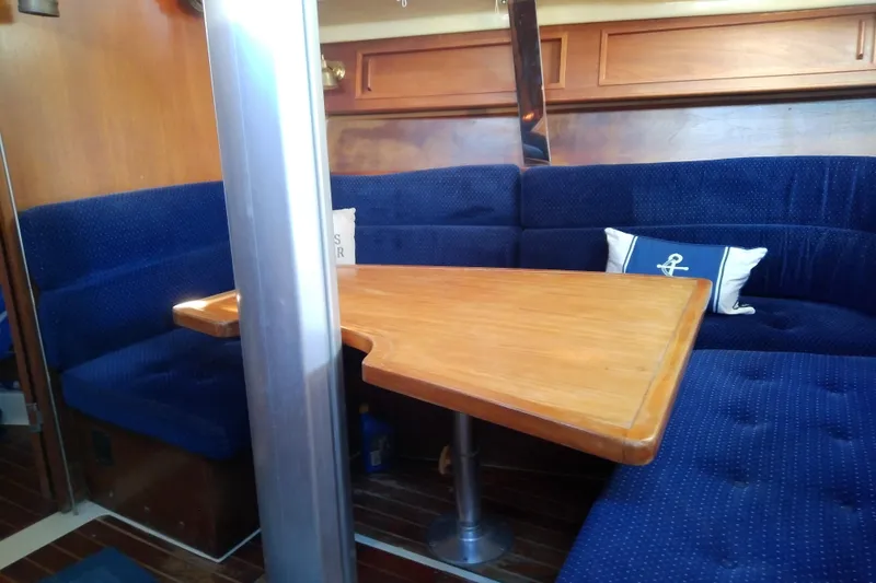 Slide: The Image of Cozy interior of 1988 Pearson 36-2 sailboat with wooden table and blue seating. - 40