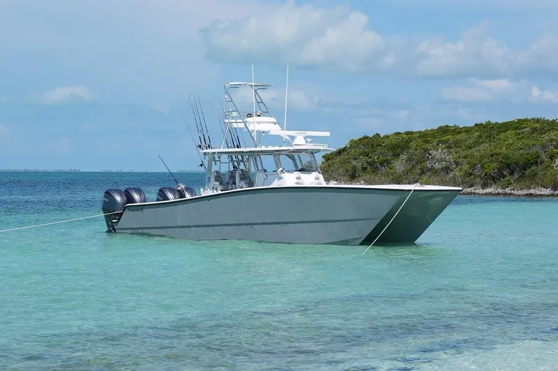 Slide: The Image of 2024 Freeman 42 boat anchored in clear turquoise water near a lush island. - 3