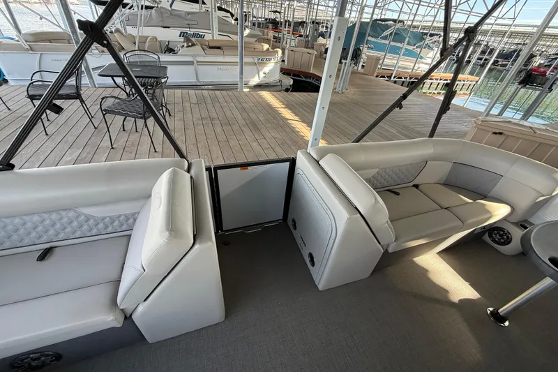 Slide: The Image of 2022 Crest Classic DLX 220 SLS pontoon boat interior with plush seating and dock view. - 11