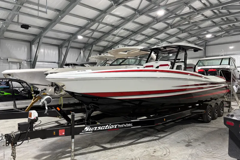 The Image of 2022 Sunsation 32 CCX boat on trailer, white with red accents, parked outdoors. - 0
