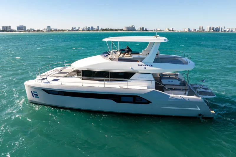 Slide: The Image of 2021 Leopard 53 Powercat yacht cruising on turquoise waters near a city skyline. - 11