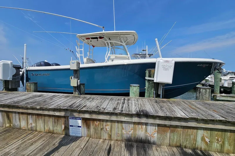 The Image of 2014 Sailfish 290 CC boat docked at a marina under a clear blue sky. - 0