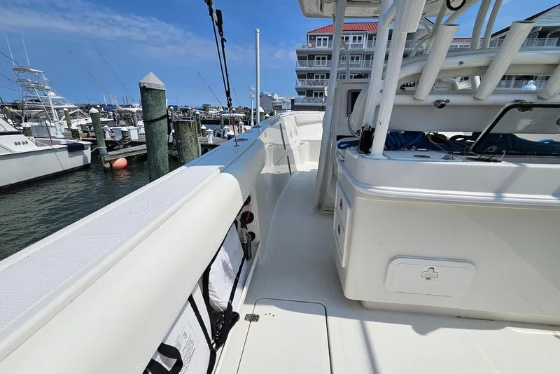 Slide: The Image of 2014 Sailfish 290 CC boat docked at marina, showcasing spacious deck and fishing equipment. - 11