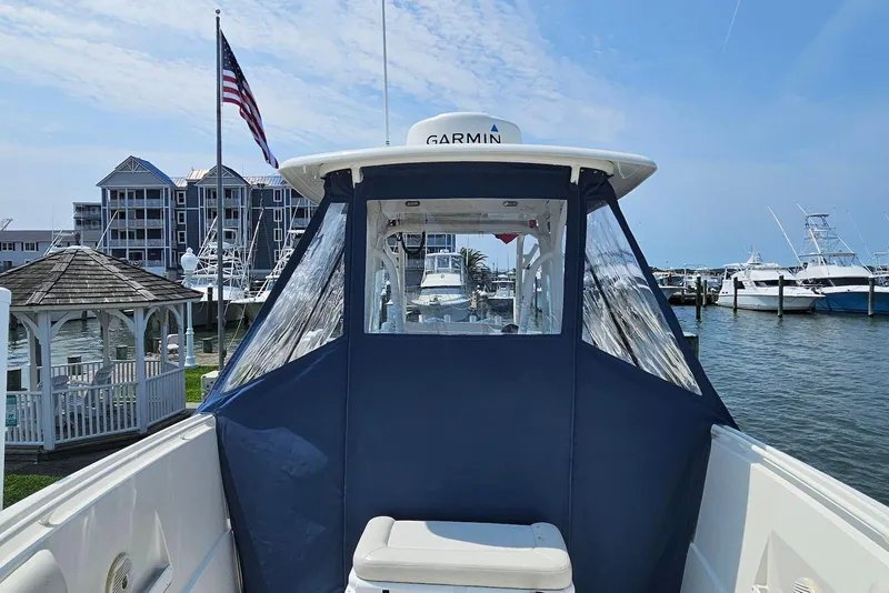 Slide: The Image of 2014 Sailfish 290 CC boat docked at marina with American flag and waterfront buildings. - 14