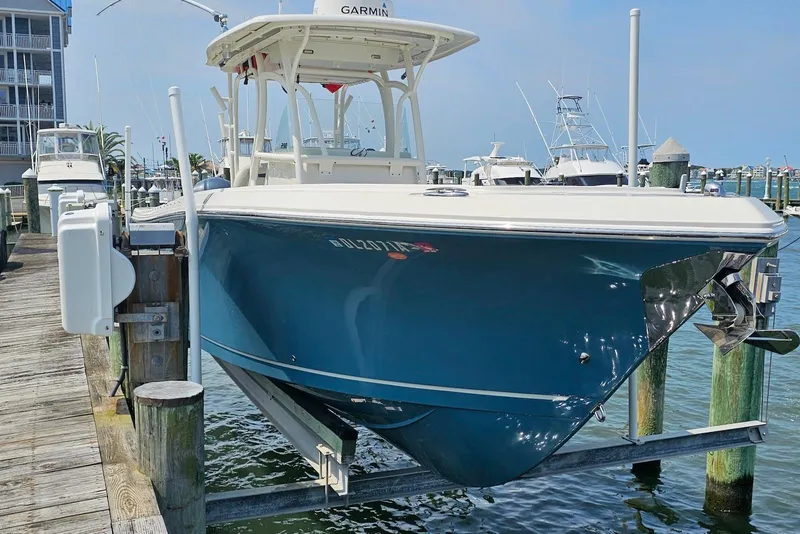 Slide: The Image of 2014 Sailfish 290 CC boat docked at marina, featuring a sleek blue hull. - 16