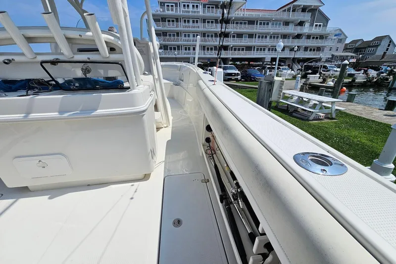 Slide: The Image of 2014 Sailfish 290 CC boat docked near waterfront buildings and picnic area. - 20