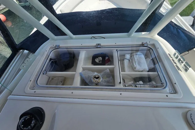 Slide: The Image of 2014 Sailfish 290 CC boat storage compartments with clear lids and organized items. - 22