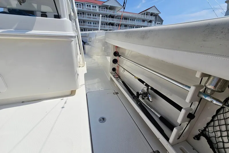 Slide: The Image of 2014 Sailfish 290 CC boat interior with fishing rod holders and white deck. - 24