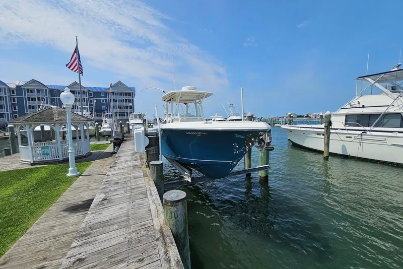 Slide: The Image of 2014 Sailfish 290 CC boat docked at marina with American flag and gazebo nearby. - 5