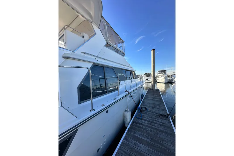 Slide: The Image of 1995 Carver 440 Aft Cabin Motor Yacht docked at marina under clear blue sky. - 14