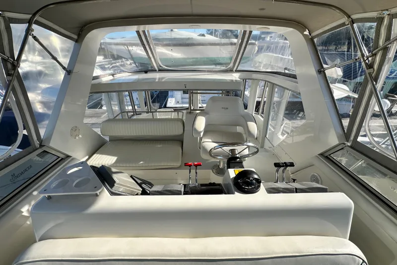 Slide: The Image of 1995 Carver 440 Aft Cabin Motor Yacht helm with white seating and steering wheel. - 30