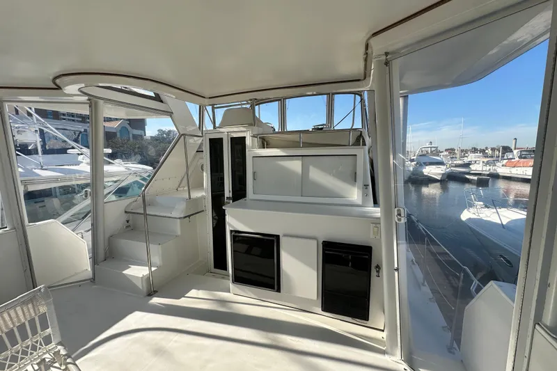 Slide: The Image of 1995 Carver 440 Aft Cabin Motor Yacht interior with marina view, featuring spacious seating and storage. - 19