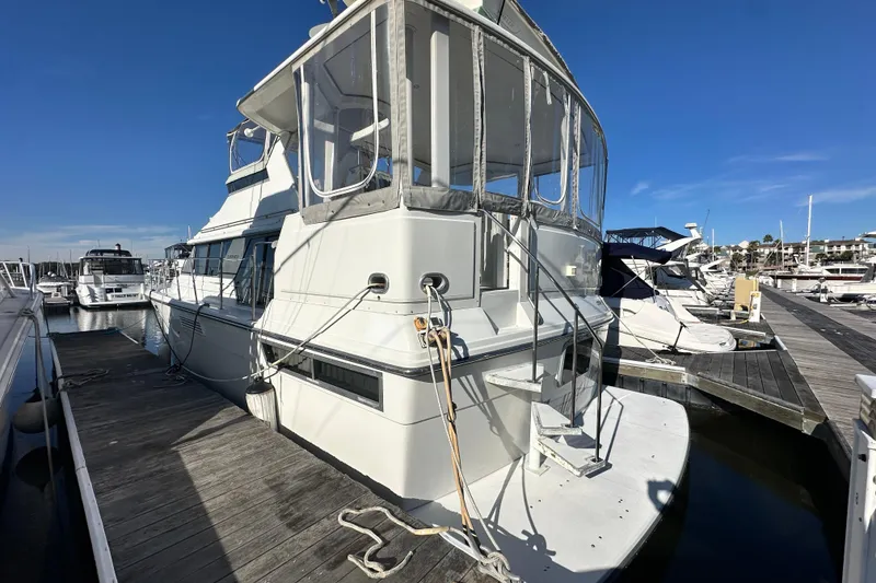 Slide: The Image of 1995 Carver 440 Aft Cabin Motor Yacht docked at marina under clear blue sky. - 2