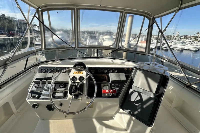 Slide: The Image of 1995 Carver 440 Aft Cabin Motor Yacht helm with marina view, showcasing controls and navigation equipment. - 24