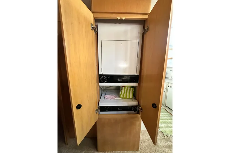 Slide: The Image of Laundry area inside 1995 Carver 440 Aft Cabin Motor Yacht with open wooden cabinet doors. - 55