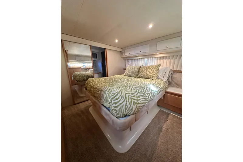 Slide: The Image of Luxurious bedroom interior of 1995 Carver 440 Aft Cabin Motor Yacht with patterned bedding. - 67