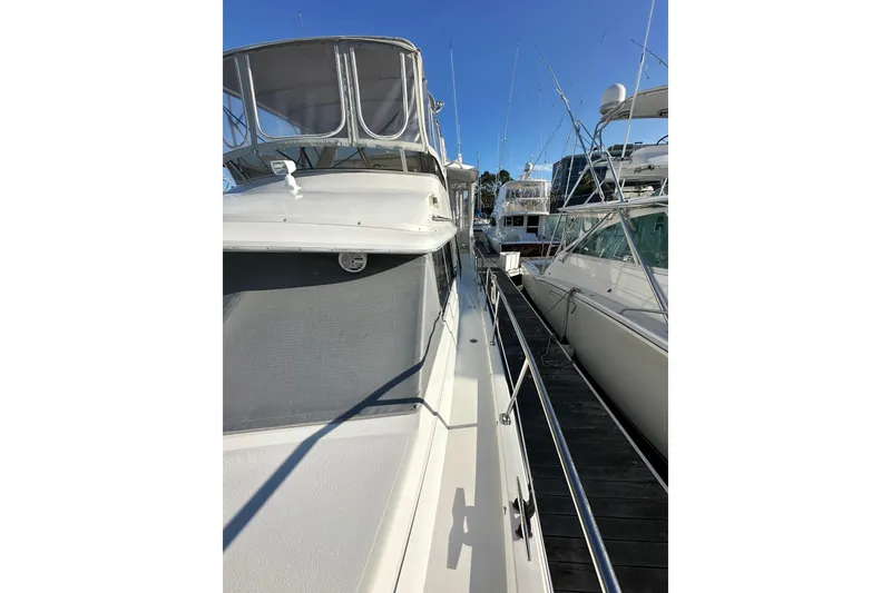 Slide: The Image of 1995 Carver 440 Aft Cabin Motor Yacht docked alongside other boats. - 7