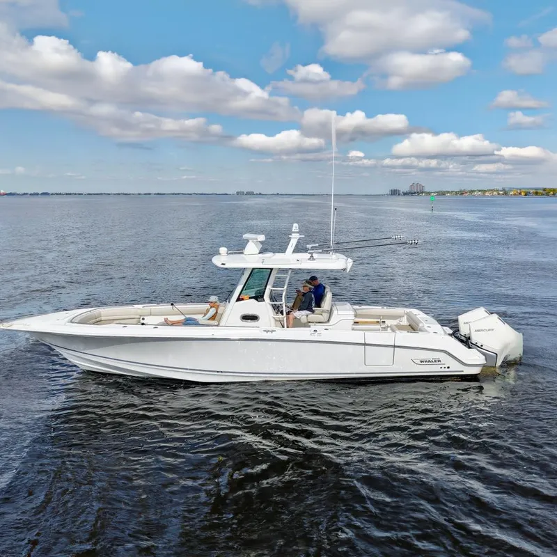 The Image of 2021 Boston Whaler 330 Outrage boat on calm water with passengers relaxing. - 0