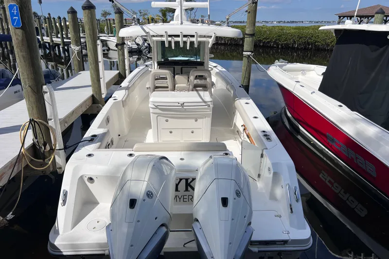 Slide: The Image of 2021 Boston Whaler 330 Outrage docked, featuring dual outboard engines and spacious deck. - 12