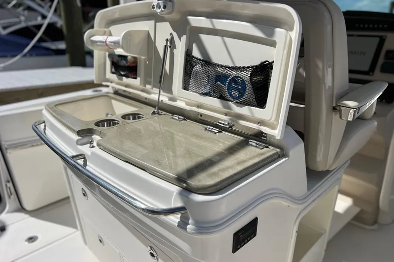 Slide: The Image of 2021 Boston Whaler 330 Outrage boat interior with open storage compartment and cup holders. - 28