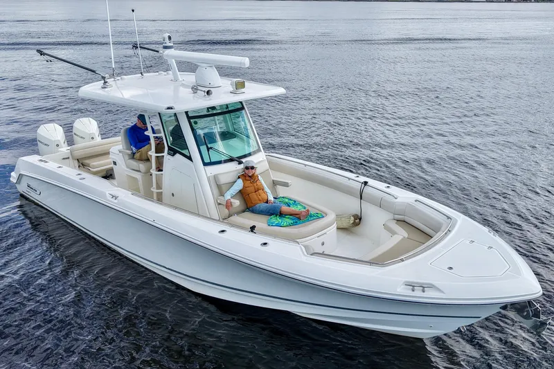 Slide: The Image of 2021 Boston Whaler 330 Outrage boat on water with two people relaxing onboard. - 6