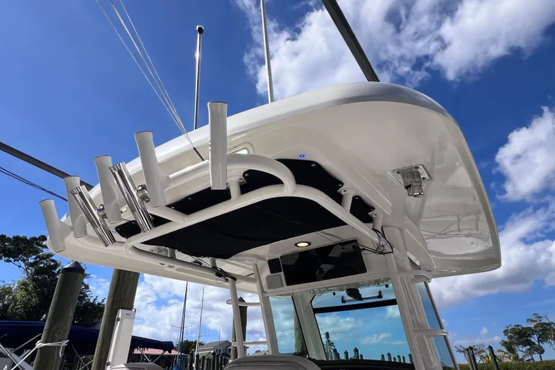 Slide: The Image of 2021 Boston Whaler 330 Outrage boat, featuring a sleek overhead structure against a blue sky. - 61