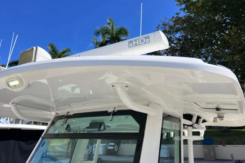 Slide: The Image of 2021 Boston Whaler 330 Outrage boat with radar and canopy, under clear blue sky. - 63