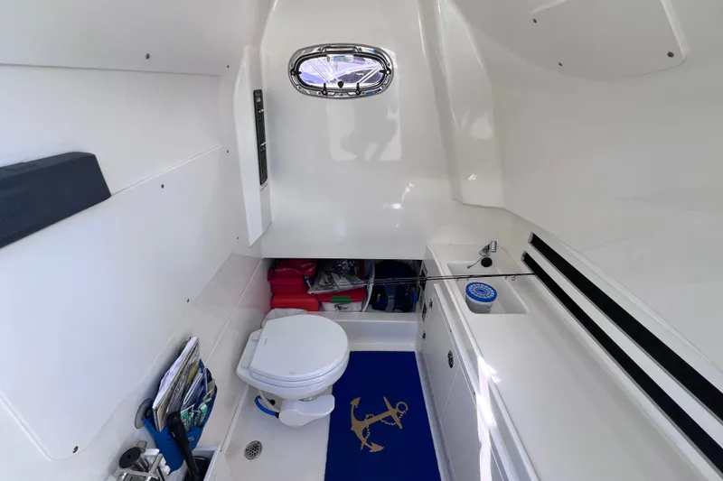 Slide: The Image of 2021 Boston Whaler 330 Outrage cabin interior with toilet, sink, and storage. - 79