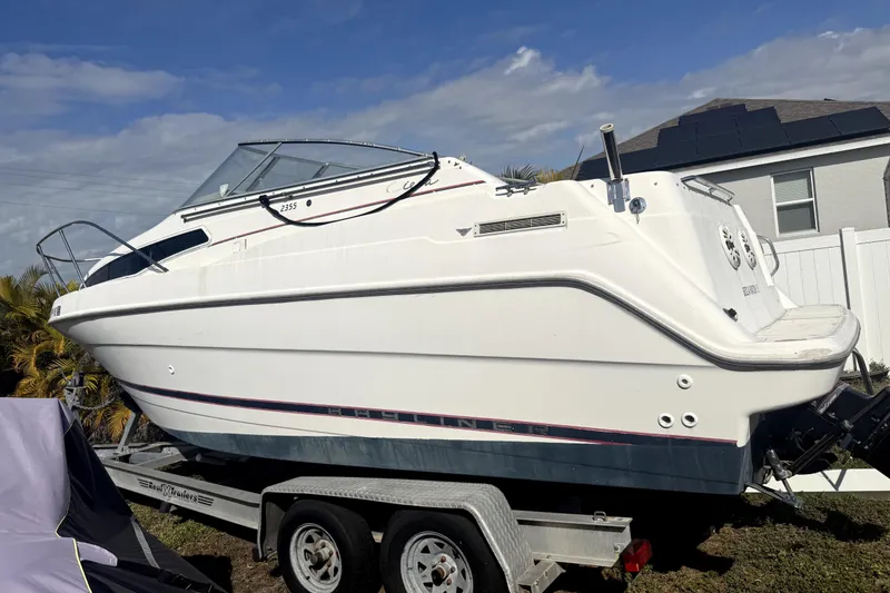 Slide: The Image of 1998 Bayliner 2355 Ciera boat on land, surrounded by trees and clear sky. - 2