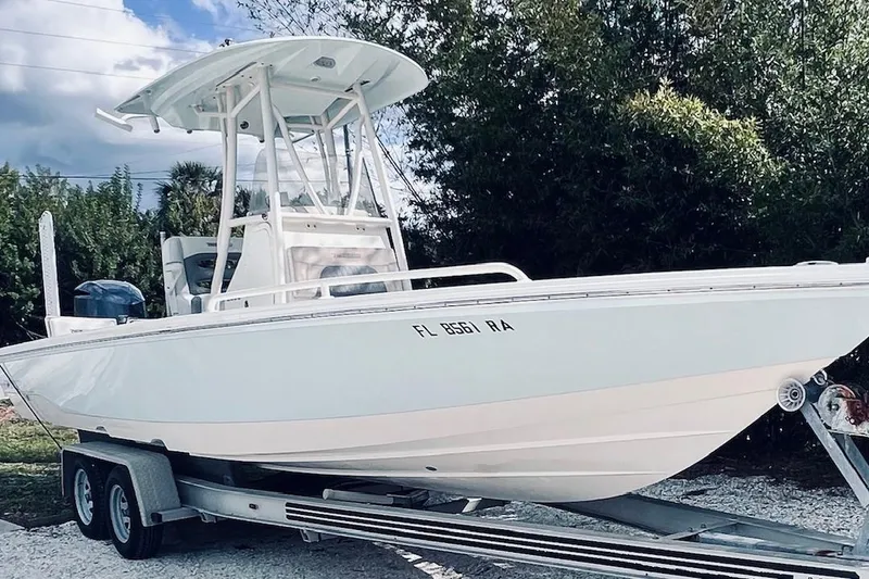 Slide: The Image of 2015 Pathfinder 2600 HPS boat on trailer, parked outdoors with trees in background. - 7