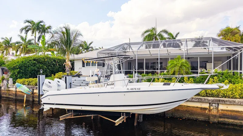 Slide: The Image of 1999 Century 2600 CC boat docked by a waterfront home with lush greenery. - 1
