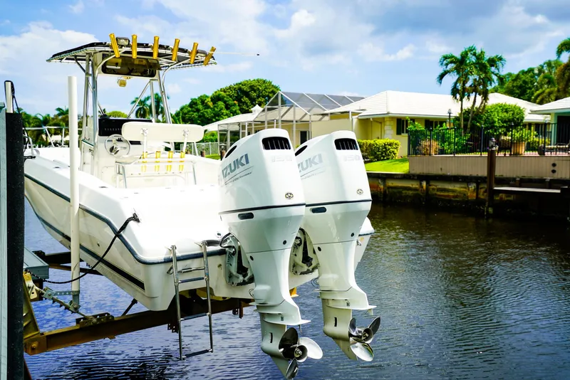 Slide: The Image of Century 2600 CC 1999 boat with dual outboard motors docked by a canal. - 12