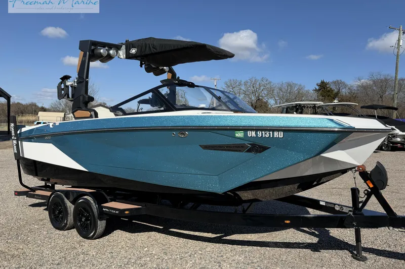 The Image of 2022 Nautique Super Air Nautique G23 boat on trailer, blue and white design. - 0
