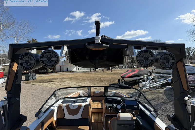 Slide: The Image of 2022 Nautique Super Air Nautique G23 boat with wakeboard rack, parked on gravel. - 23