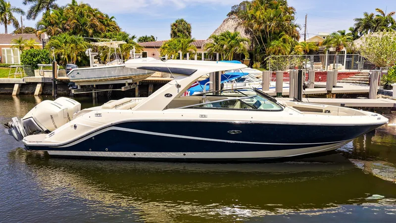 Slide: The Image of 2022 Sea Ray SLX 310 OB boat docked in a scenic marina setting. - 29