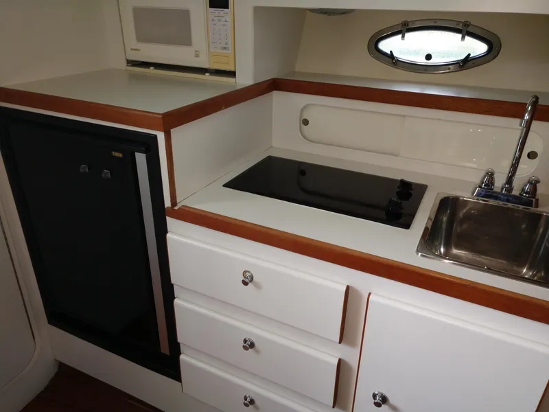 Slide: The Image of 1996 Tiara Yachts 3100 EXPRESS kitchen with stove, sink, microwave, and storage drawers. - 12