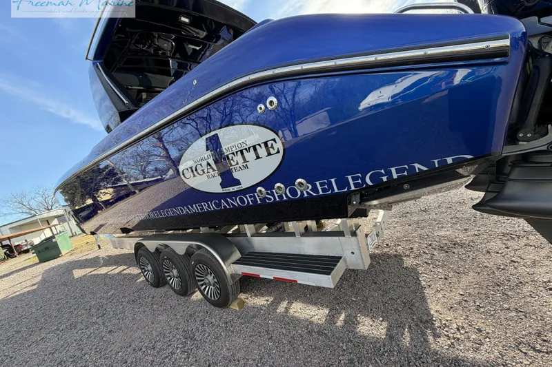 Slide: The Image of 2024 Cigarette 41' Nighthawk boat on trailer, showcasing sleek blue design and triple-axle wheels. - 14