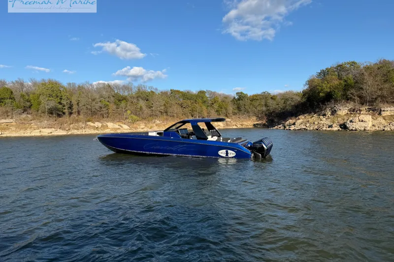 Slide: The Image of 2024 Cigarette 41' Nighthawk boat on a serene lake with a wooded shoreline. - 30