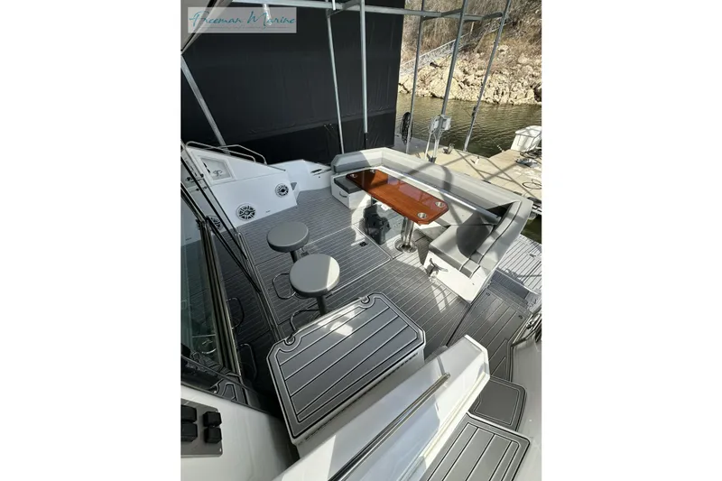 Slide: The Image of 2022 Cruisers Yachts 60 Cantius deck with seating and table, docked by water. - 55