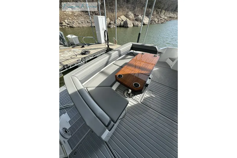 Slide: The Image of 2022 Cruisers Yachts 60 Cantius deck with seating and wooden table by the water. - 57
