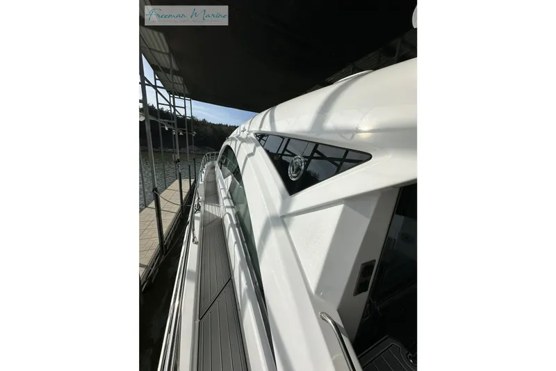 Slide: The Image of 2022 Cruisers Yachts 60 Cantius side view, docked under a canopy. - 54