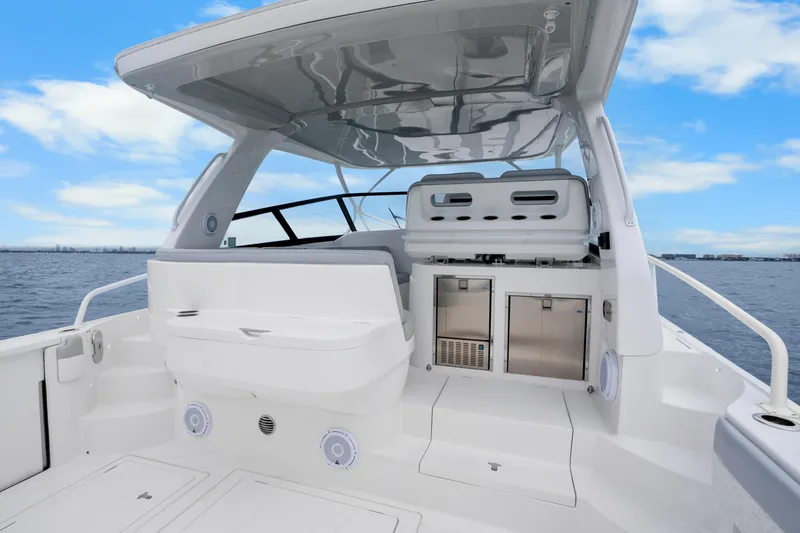 Slide: The Image of 2024 Intrepid 477 Evolution boat interior with seating and storage, under a clear blue sky. - 7