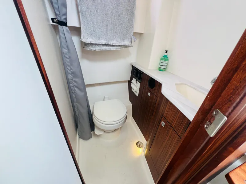 Slide: The Image of 2022 Pursuit S 358 Sport boat bathroom with toilet, sink, and wooden cabinetry. - 10