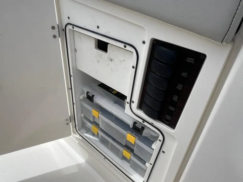 Slide: The Image of 2022 Pursuit S 358 Sport storage compartment with organized tackle boxes and control panel. - 18
