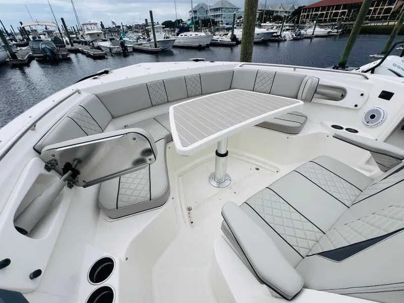 Slide: The Image of 2022 Pursuit S 358 Sport boat interior with elegant seating and table, docked at marina. - 36