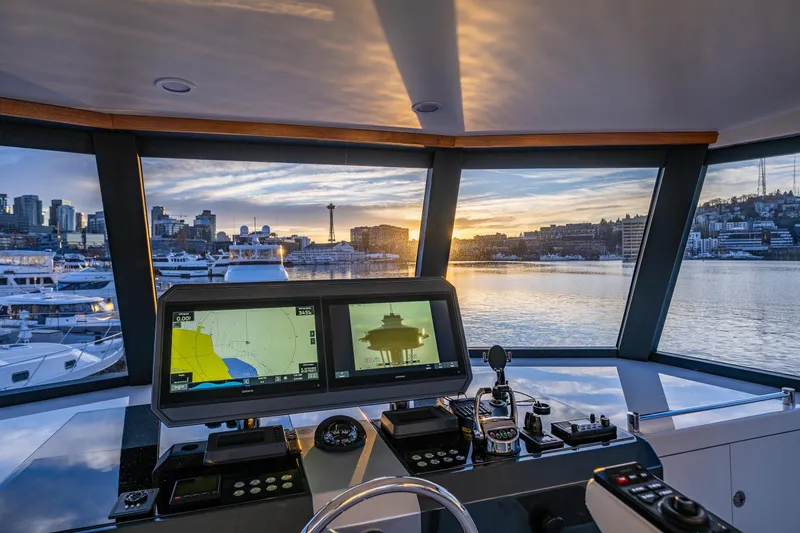 Slide: The Image of Pilothouse view from 2017 Ocean Alexander 72, showcasing navigation screens and city skyline at sunset. - 14