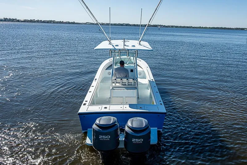 Slide: The Image of 2000 Regulator 26 Forward Seating boat on calm water, rear view with dual engines. - 3